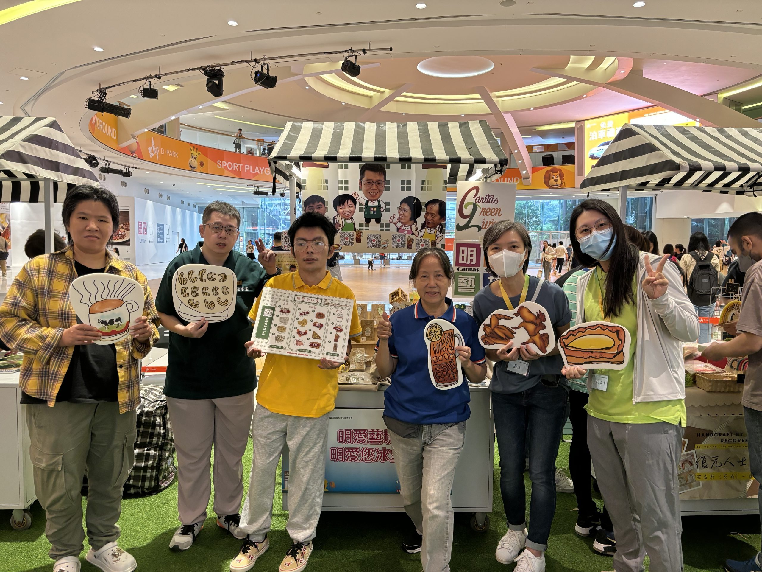 Boss Mun and Boss Kin took a group photo with volunteers and staff holding a sign printed with food from the restaurant.