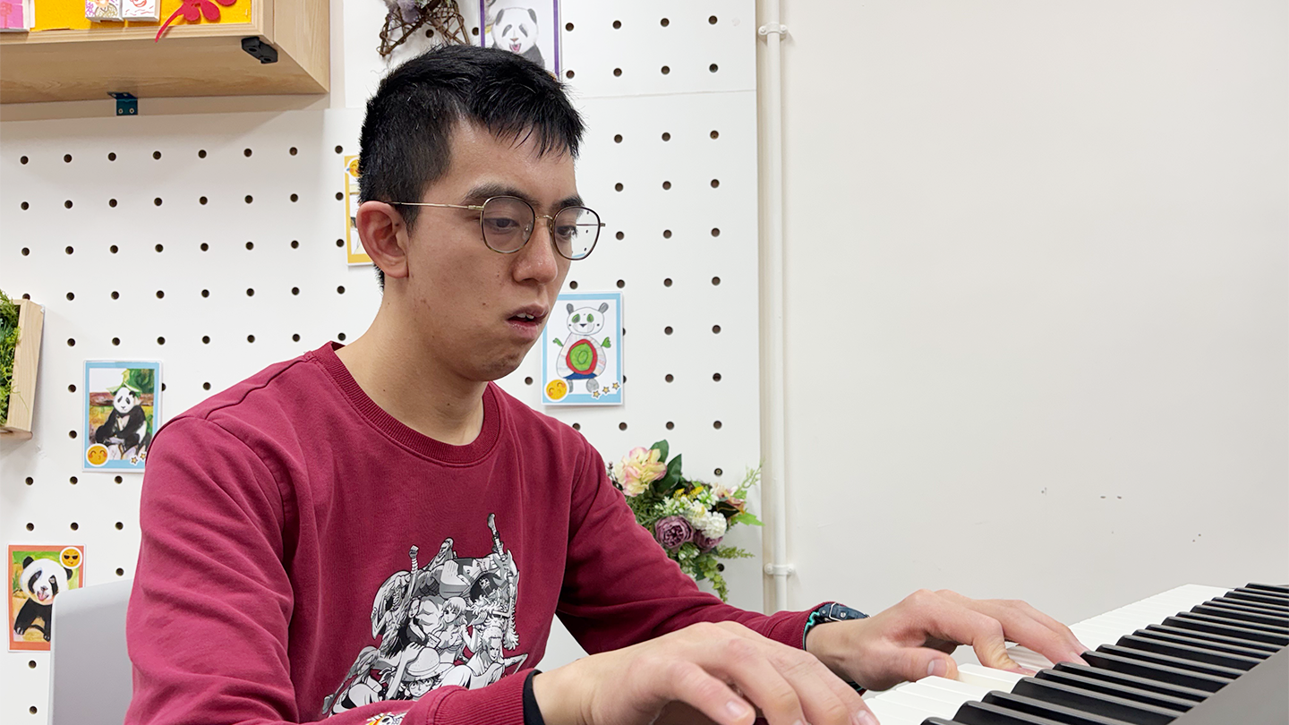老闆阿邦戴著眼鏡，專注地彈奏鋼琴，展現出音樂的熱情與才華。